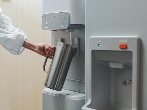 a person is putting a cup into a machine at SOKI Kanazawa in Kanazawa