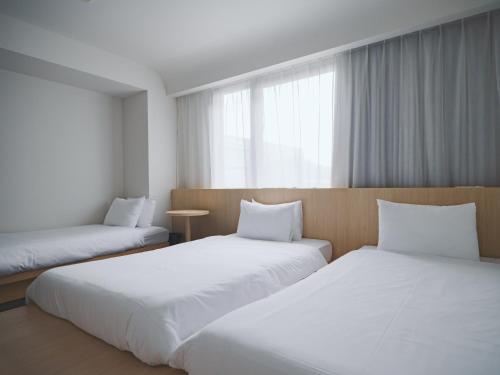 a room with two beds and a window at SOKI Kanazawa in Kanazawa