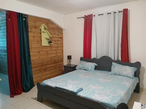 a bedroom with a bed and red curtains at résidence IDIMAH in Sada