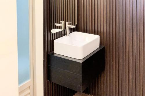 a bathroom with a white sink on a wall at Berlian Abadi Hotel by Sinergi in Banyuwangi