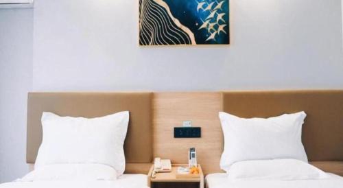 a hotel room with two beds with white pillows at GreenTree Inn Jiaxing Tongxiang Tudian Express Hotel in Jiaxing