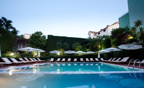 a large swimming pool with lounge chairs and umbrellas at Orchidea Hotel in Tirana