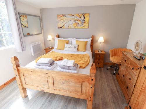 a bedroom with a wooden bed with towels on it at Angel's Retreat in Alford