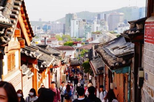 a crowd of people walking down a street with buildings at Spring Light in Seoul