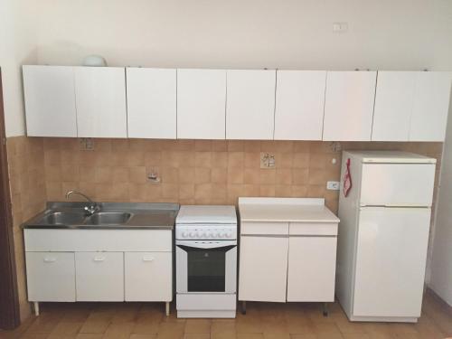 a kitchen with white cabinets and a sink and a refrigerator at Il Gamberetto in Principina a Mare