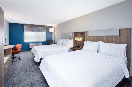 a hotel room with two beds and a desk at Holiday Inn Express Hotel & Suites Defiance by IHG in Defiance