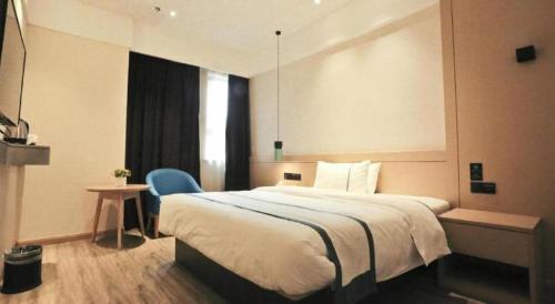 a bedroom with a large bed and a blue chair at City Comfort Inn Wuhan Wansongyuan Wangjiadun East Metro in Wuhan