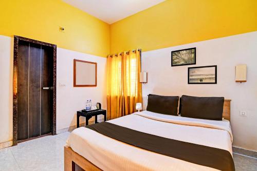 1 dormitorio con 1 cama grande y paredes amarillas en Hotel O Modern Stay Near ITER, en Bhubaneshwar