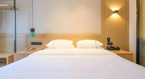 a large white bed with two pillows in a room at City Comfort Inn Wuhan Wansongyuan Wangjiadun East Metro in Wuhan