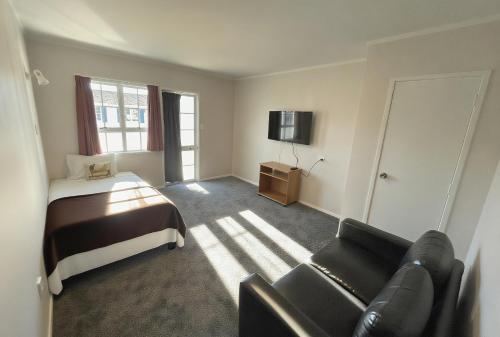 a bedroom with a bed and a couch and a television at Boundary Court Motor Inn in Hamilton