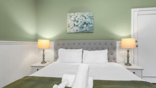 a bedroom with a large white bed with two lamps at Little Plum Cottage in Apollo Bay
