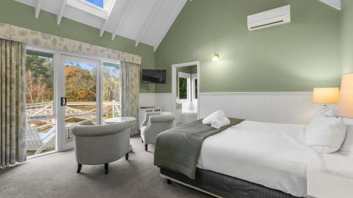 a bedroom with a bed and chairs and a balcony at Little Plum Cottage in Apollo Bay