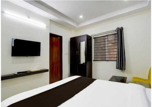 a bedroom with a bed and a flat screen tv at Townhouse Sartha Convention Centre Formerly GMR Serenity Suits in Hyderabad