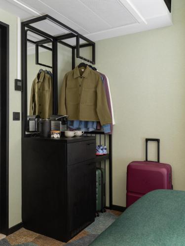 a room with a dresser with a jacket and a suitcase at Numa Brussels Royal Galleries in Brussels