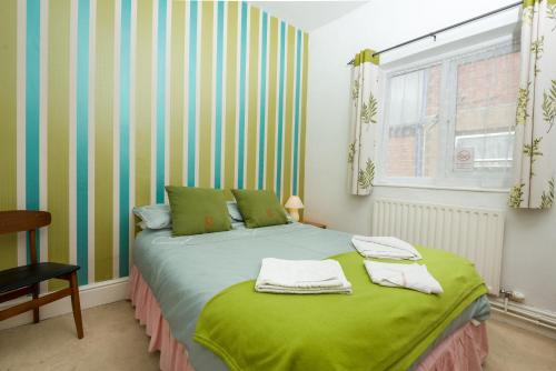a bedroom with a green bed with towels on it at UK Travel & Hospitality LTD TA Canberra Hotel in Blackpool