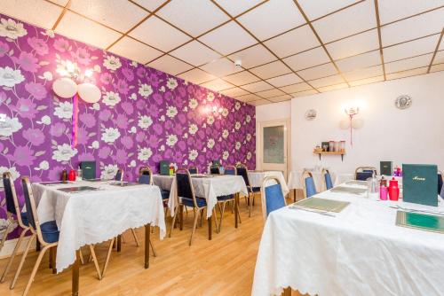 a room with tables and chairs and a purple wall at UK Travel & Hospitality LTD TA Canberra Hotel in Blackpool