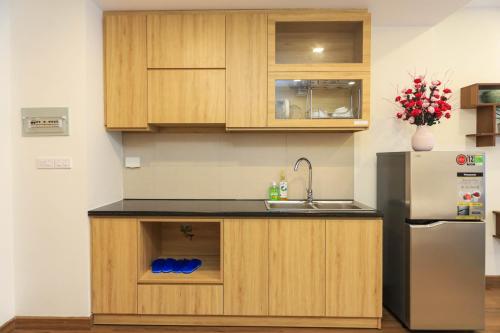 a kitchen with wooden cabinets and a refrigerator at FLC Sea Tower Quy Nhơn Seaview Apartment in Quy Nhon