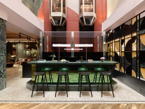 a dining room with a green table and stools at Numa Brussels Royal Galleries in Brussels