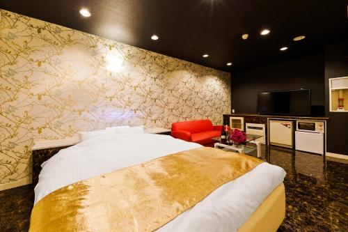 a bedroom with a bed and a red chair at HOTEL Lien in Ashiya