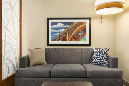 a living room with a gray couch and a painting at Hyatt Place Columbia/Downtown/The Vista in Columbia