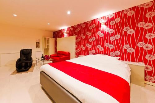 a bedroom with a bed and a red wall at HOTEL Lien in Ashiya