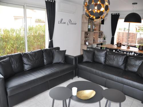 Una sala de estar con un sofá de cuero negro y una mesa. en Villa in Le Grau du Roi near Flamingo Lagoon, en Le Grau-du-Roi