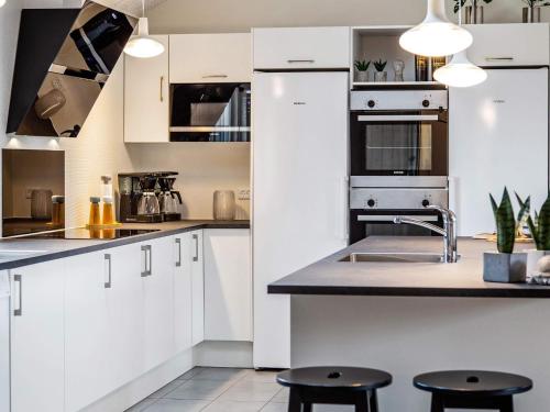 a kitchen with white cabinets and a sink and two stools at 22 person holiday home in Idestrup in Marielyst