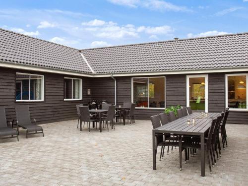 a patio with tables and chairs and a building at 22 person holiday home in Idestrup in Marielyst