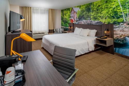 a hotel room with a bed and a flat screen tv at Clarion Pointe Beckley in Beckley