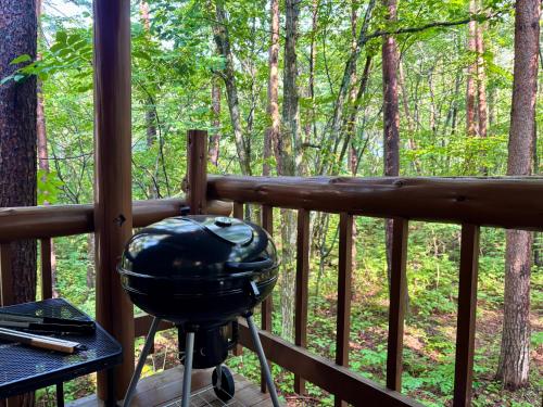 a grill on the porch of a cabin in the woods at Forest Paw北軽井沢 広大な庭とウッドデッキのログハウス 専用キッズスペース 庭でのアスレチックやクワガタ採集 in Tsumagoi