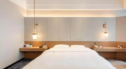 a bedroom with a large white bed and a bath tub at Grand Metropark Hotel Chongqing in Chongqing