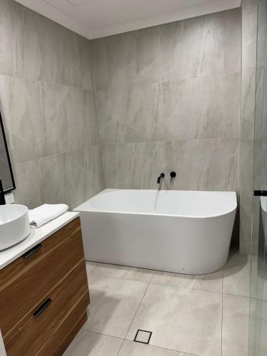 a bathroom with a white tub and a sink at Oceanic Escape Top Floor 2 mins from beach in Perth