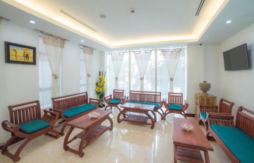 a living room with chairs and tables and a tv at Phnom Penh Katari Hotel in Phnom Penh