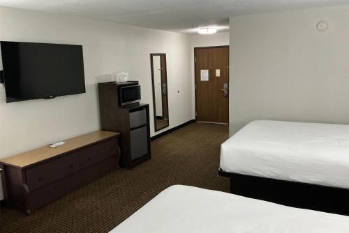 a hotel room with two beds and a flat screen tv at Tombstone Grand Hotel, a Baymont by Wyndham in Tombstone