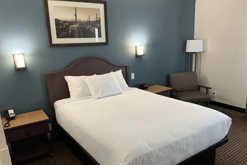 a bedroom with a large white bed and a chair at Tombstone Grand Hotel, a Baymont by Wyndham in Tombstone
