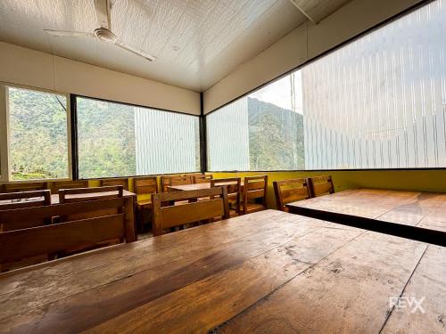 een leeg klaslokaal met tafels, stoelen en ramen bij The Sona Heli Resort in Rudraprayāg