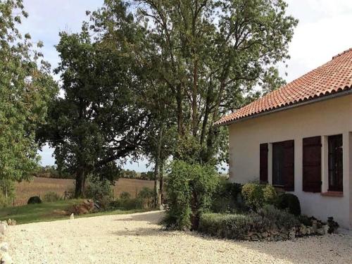 a white house with trees and a field in the background at Cozy French Escape in Monfort in Monfort