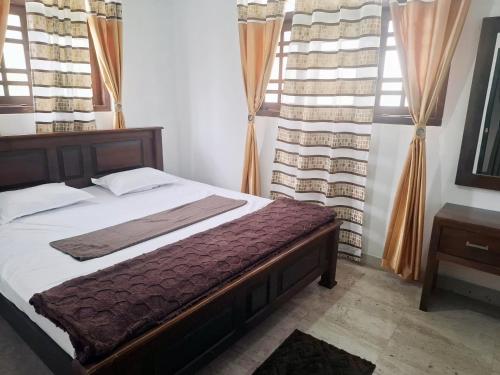 a bedroom with a bed and two windows at Misty Morning Villa - Ella in Medaperuwa