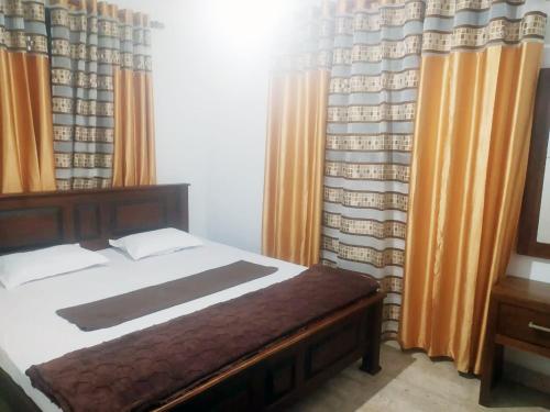 a bedroom with a bed and curtains and a television at Misty Morning Villa - Ella in Medaperuwa