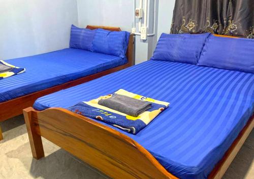 two beds in a room with blue sheets and blue pillows at Family Batcave Homestay in Battambang