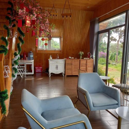 a living room with two chairs and a kitchen at WindHill Homestay Bảo Lộc - Căn Villas Nhà Gỗ in Bon Tan Djiran B