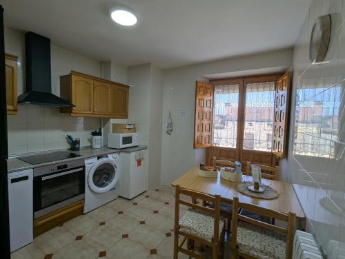 a kitchen with a table and a washing machine at Tierra de pinares in Vinuesa