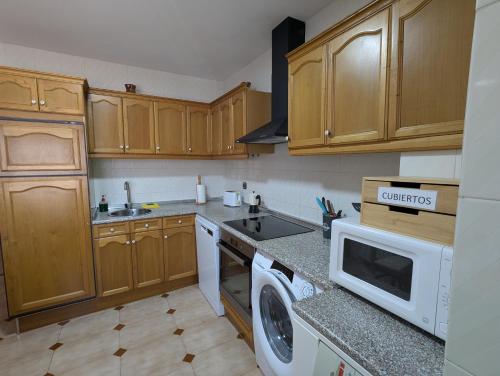 a kitchen with wooden cabinets and a washer and dryer at Tierra de pinares in Vinuesa