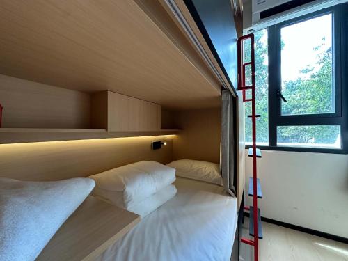 a room with two beds and a window and a ladder at Amic Girls' Hostel (Shenzhen Shekou Sea World) in Shenzhen