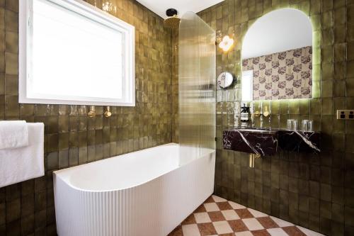 a bathroom with a tub and a window at Medusa Hotel Sydney in Sydney