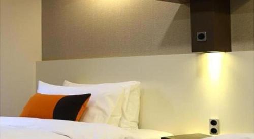 a bedroom with a bed with an orange and black pillow at KT&G Sangsangmadang Chuncheon Stay (Korea Quality) in Chuncheon