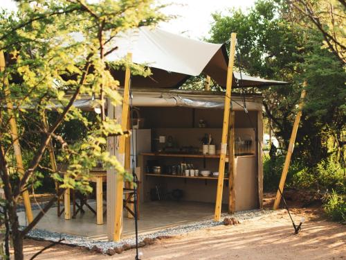 a small tent with a table and a refrigerator at The Leadwood Safari Camp in Dinokeng Game Reserve