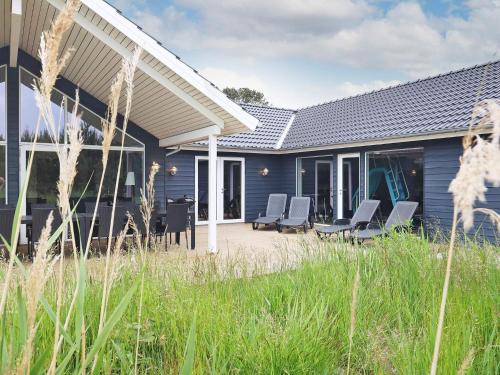 a blue house with chairs on a patio at 22 person holiday home in Jerup in Jerup