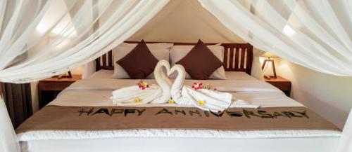 a bed with two swans made out of towels at Lonthar B&B - Adults Only in Riung