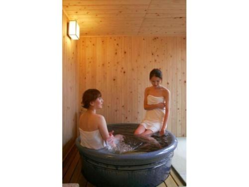 two women sitting in a hot tub in a sauna at Hirata Maple Hotel in Izumo